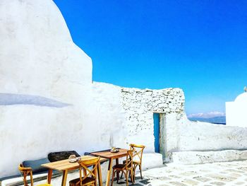 Chairs and table against clear blue sky