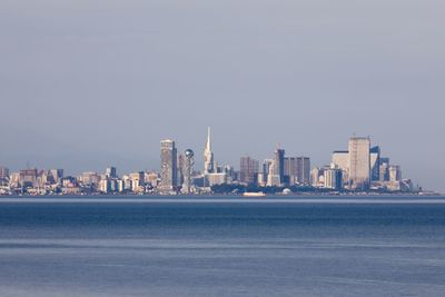 Sea by modern buildings against clear sky