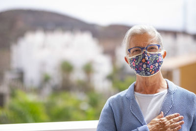 Portrait of senior woman wearing mask standing outdoors