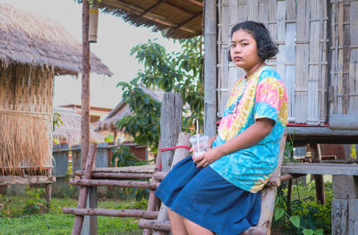 Portrait of young woman standing against tree