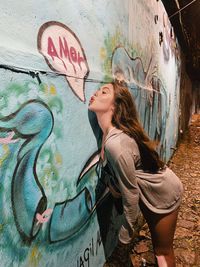 Young woman with graffiti on wall