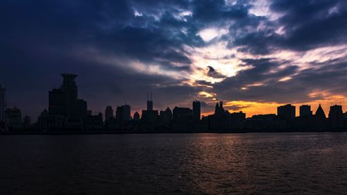 Scenic view of lake against cloudy sky during sunset in city