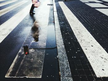 Pedestrian and road signal reflecting in puddle on street
