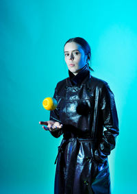 Portrait of young woman with balloons against blue background