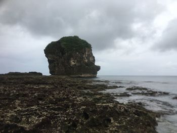 Rock formation on sea shore against sky
