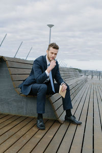 Portrait of young businessman sitting on bench