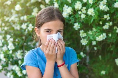 Sick girl sneezing against plant