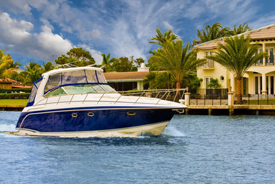 Built structure by palm trees against sky