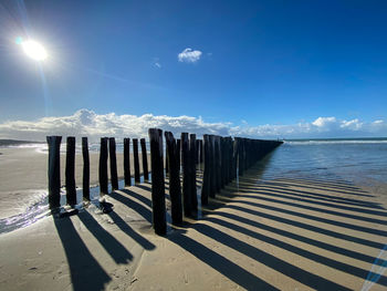 Wooden posts on beach against sky