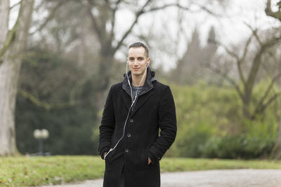 Portrait of young man standing against trees