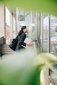 Smiling businesswoman opening door and entering office