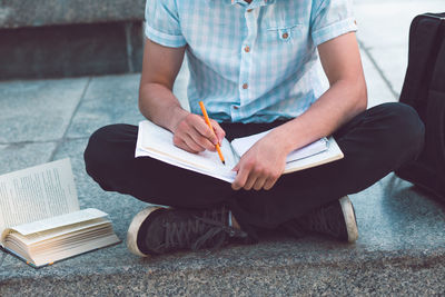 Low section of man sitting on book