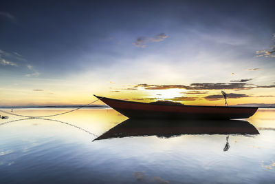 Boat moored on sea against sky during sunset