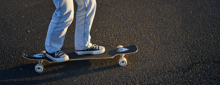 Low section of man skateboarding on road