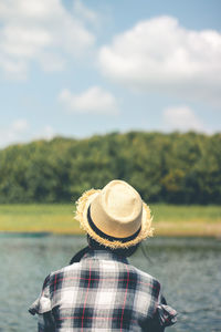 Rear view of woman wearing hat against lake