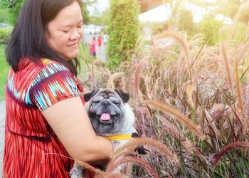 Smiling woman with dog by plants