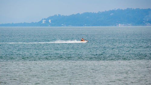 People riding jet boat on sea against sky