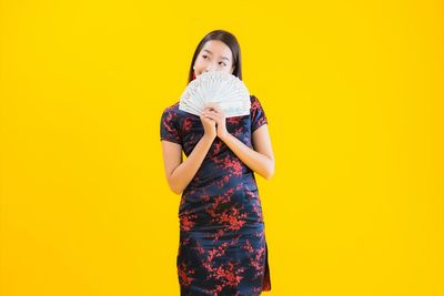 Portrait of woman standing against yellow background