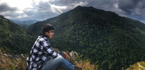 Young man looking at mountains against sky