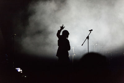 Silhouette singer gesturing at music concert