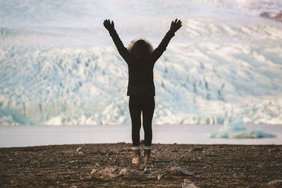 Woman with arms raised standing on landscape against sky