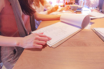 Midsection of woman reading book while sitting on table