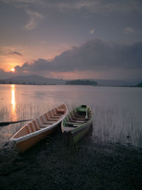 Boat moored on sea against sky during sunset