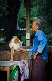 Side view of woman with cat standing by table