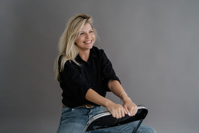 Portrait of young woman sitting against wall