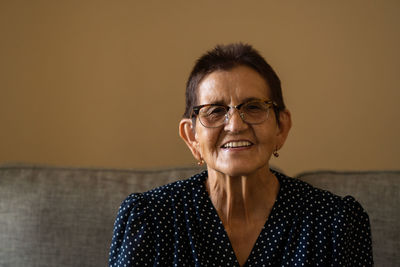 Portrait of smiling senior woman in eyeglasses sitting at home