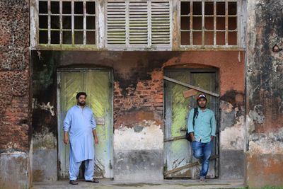 Portrait of smiling men while standing outside house