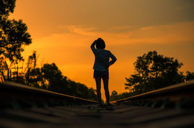 Full length of silhouette woman standing against orange sky