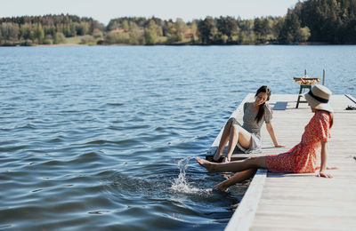 Female friends relaxing on jetty barefoot