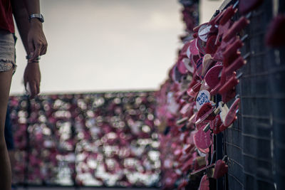 Cropped image of man and woman by padlocks on footbridge railing