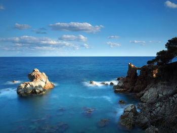 Rock formations in sea against blue sky