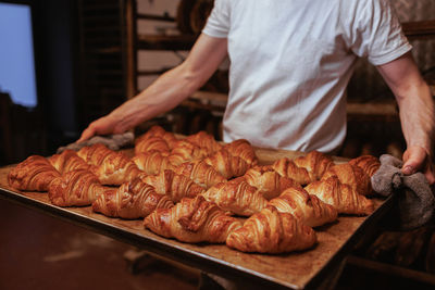 Midsection of baker holding fresh croissants