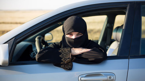 Portrait of woman wearing hijab sitting in car