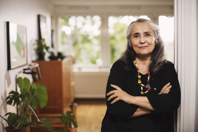 Portrait of confident senior woman standing arms crossed at home