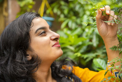 Side view of smiling young woman holding plant