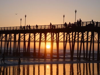 Silhouette pier over sea against sky during sunset