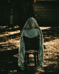 Rear view of man sitting on chair in forest