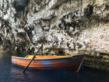 Boat moored on shore against cave