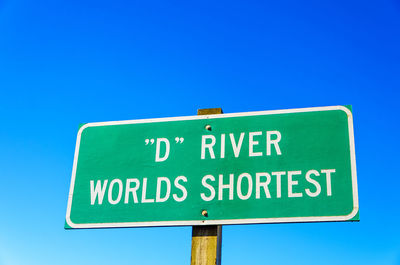 Low angle view of information sign against clear blue sky