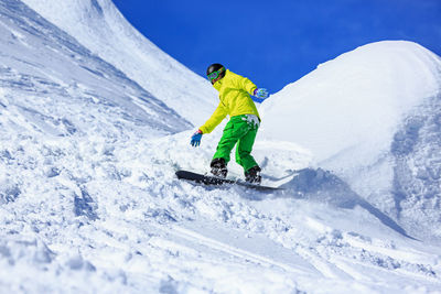 Low angle view of young man skiing on snowcapped mountains during winter