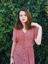 Beautiful young woman standing against plants