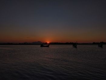 Silhouette sailboats in sea against sky during sunset