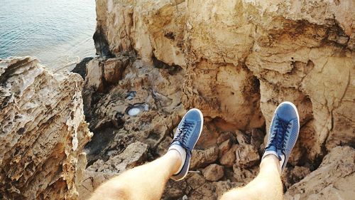 Low section of man sitting on cliff