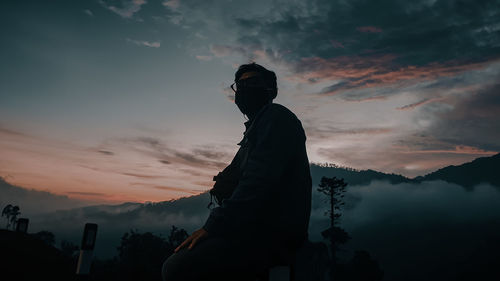 Silhouette man standing on mountain against sky during sunset