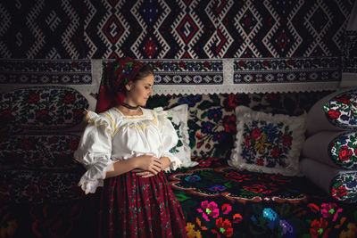 Young woman in romanian clothing standing at home