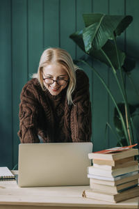 Smiling businesswoman working on laptop leaning at desk in home office